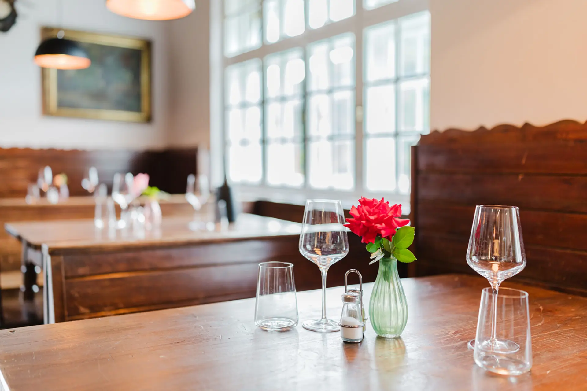 Gedeckter Holztisch mit roter Rose in der Gaststube des Aggsteiner Hofs